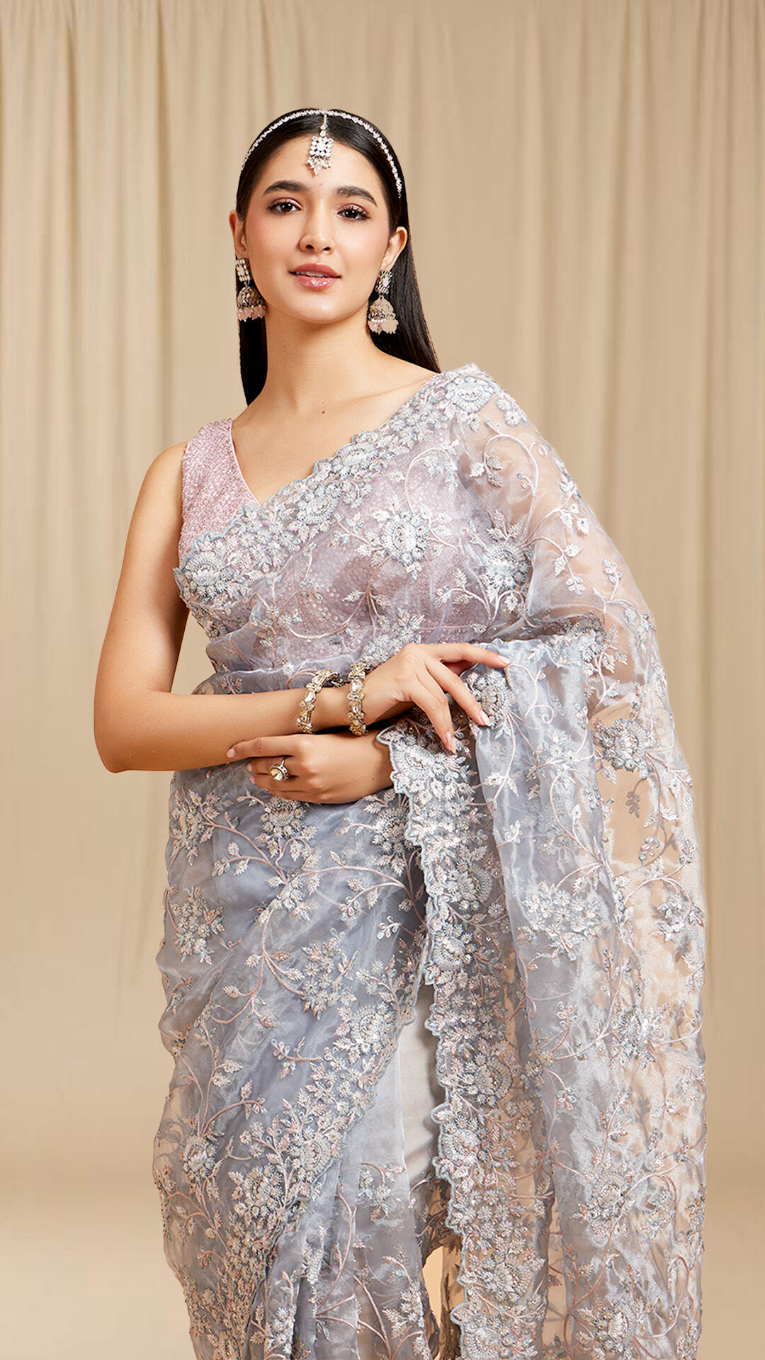 A women wearing a beautifull silver saree with beautifull flowers pattern on it